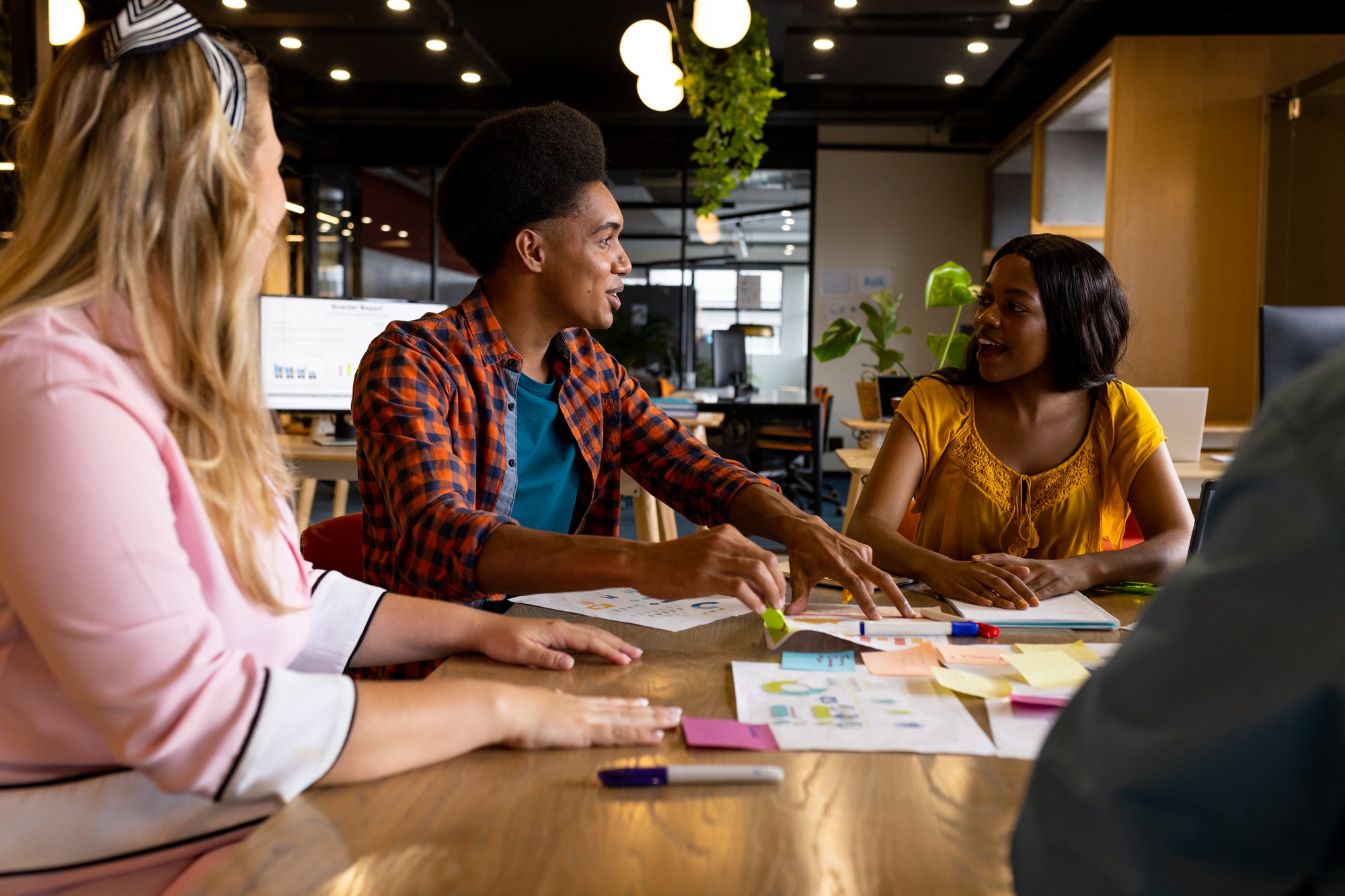 Diverse creative colleagues in discussion brainstorming using tablet and notes in office